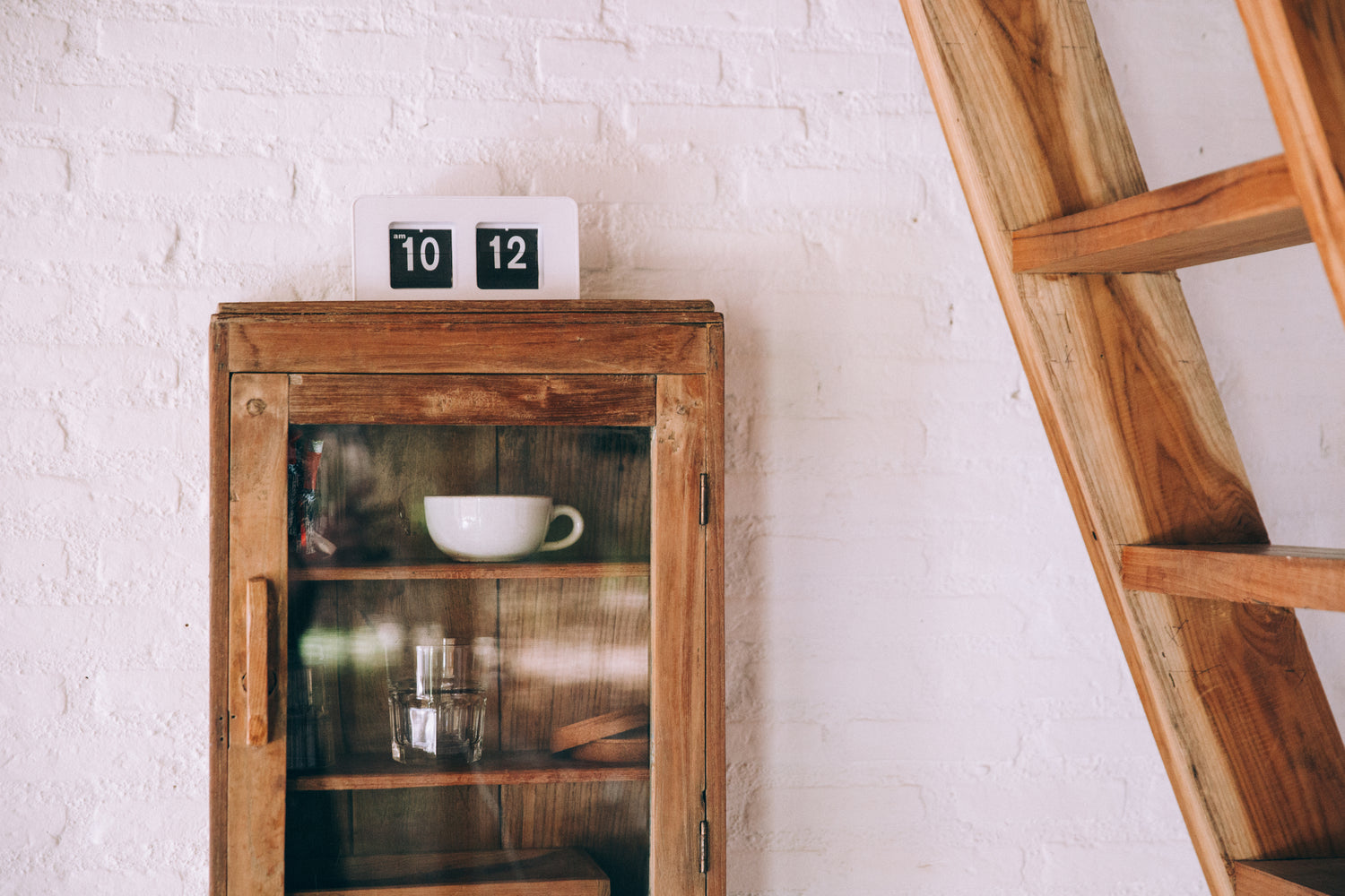 mur blanc en pierre avec un meuble en bois et une échelle en bois