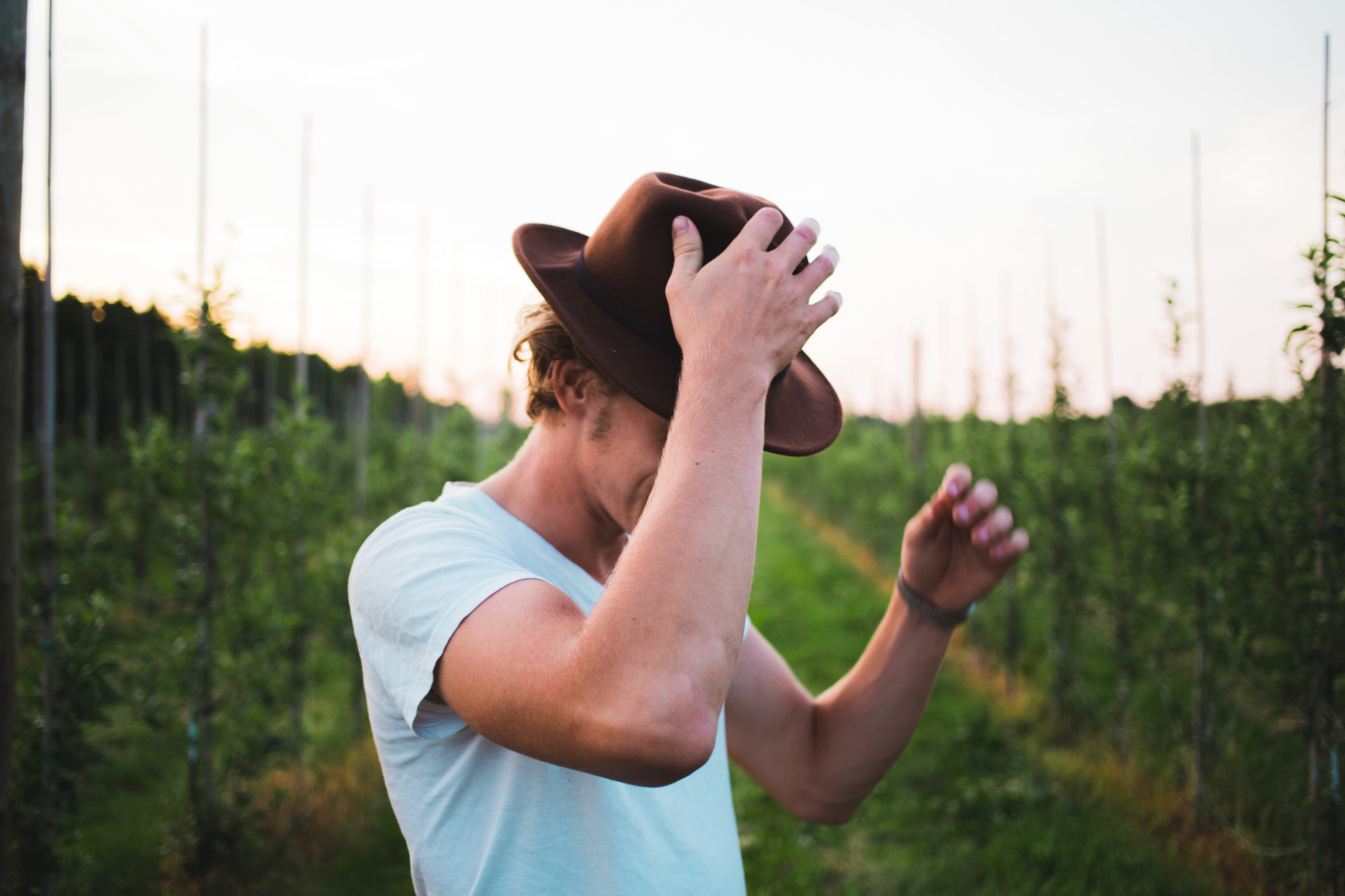 un homme qui se met un chapeau sur la tee au milieu d'un champ